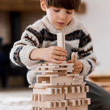 child playing with architectural wooden blocks by wooden story