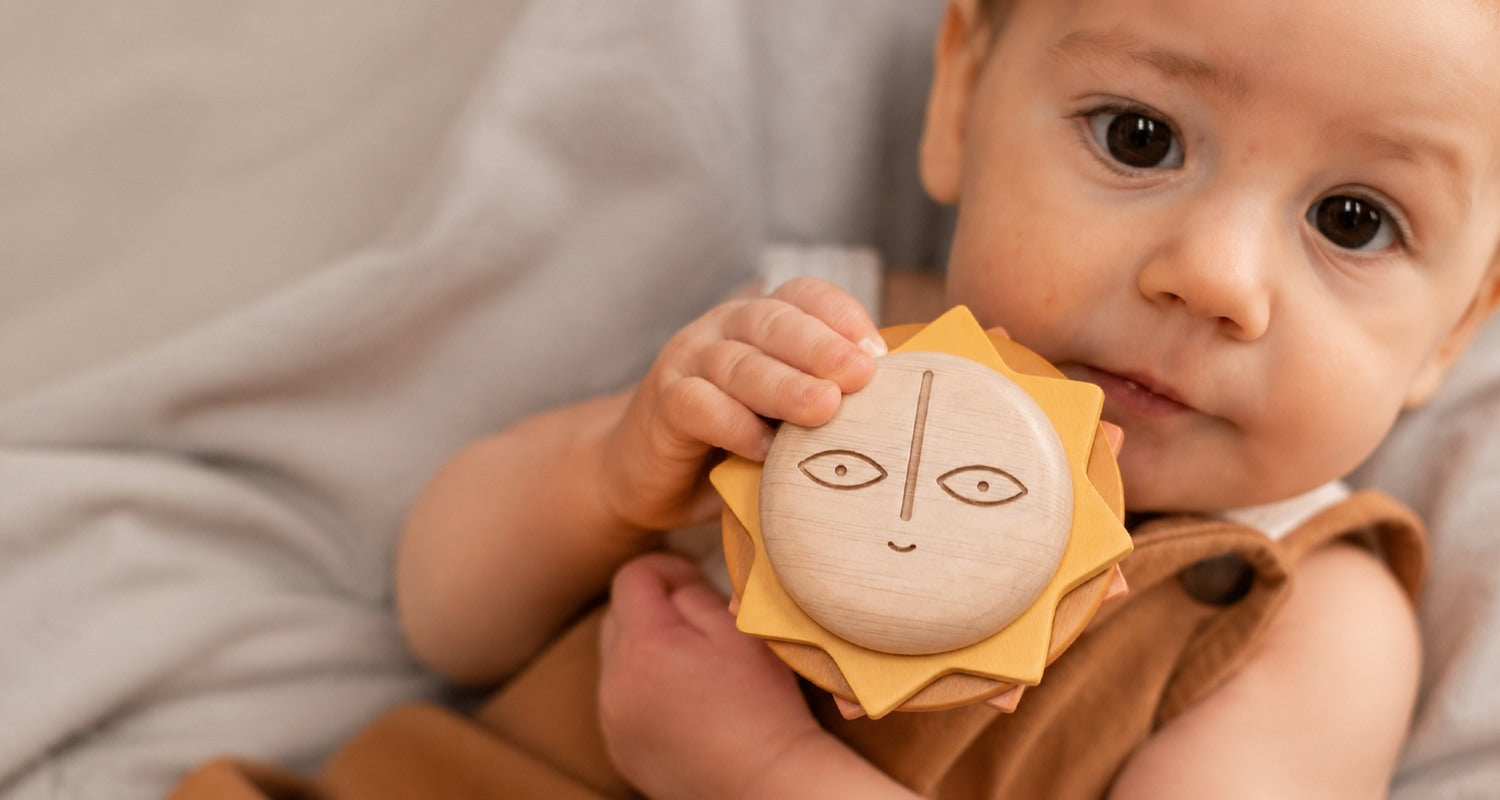 Baby holding the Here Comes the Sun natural wooden teether