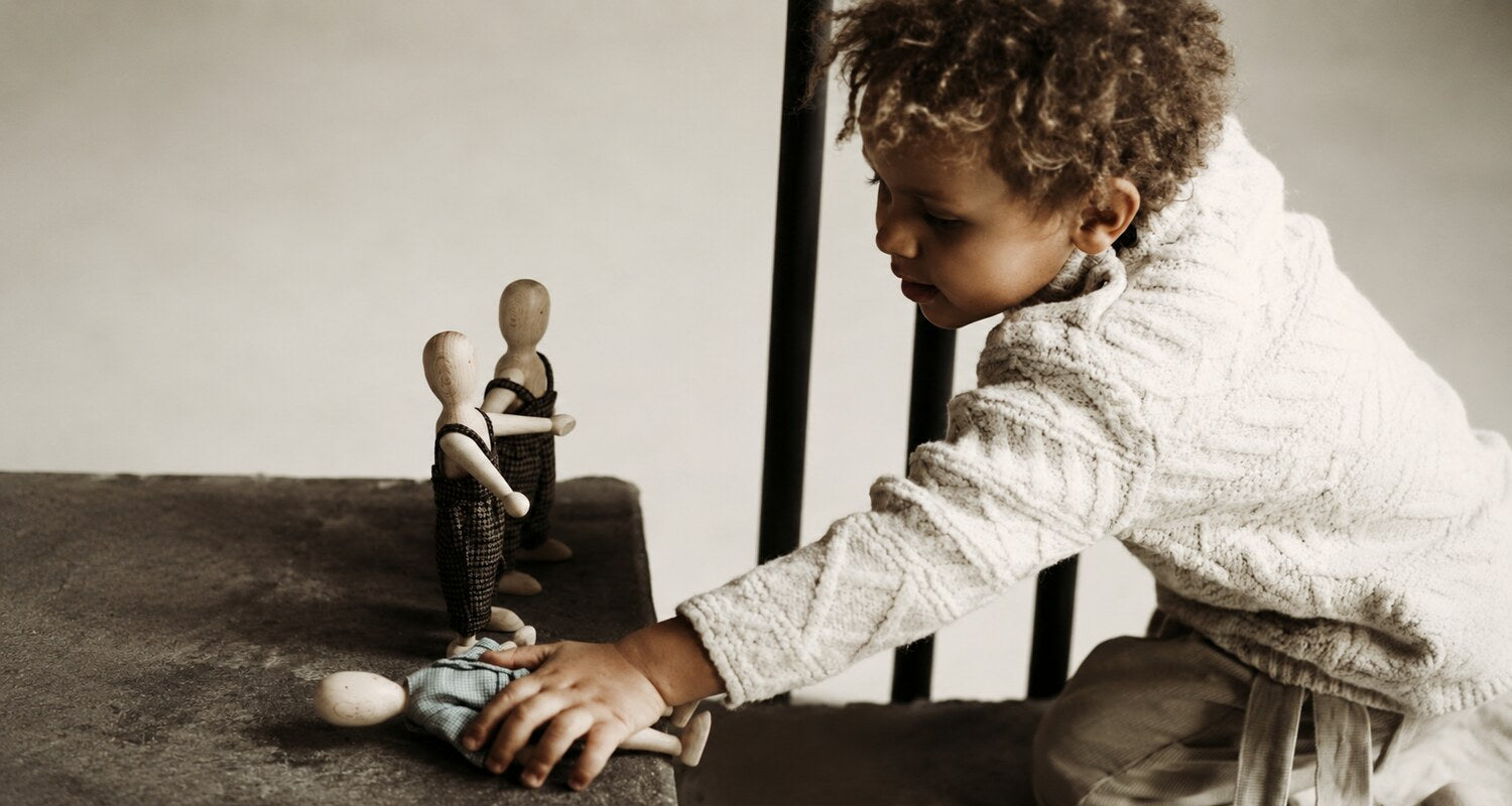 Child creating stories with simple wooden dolls during imaginative play