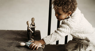 Child creating stories with simple wooden dolls during imaginative play