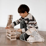 child playing with architectural wooden blocks by wooden story