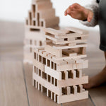 child playing with architectural wooden blocks by wooden story