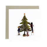 Greeting card with illustration of children decorating a Christmas tree with a star on top by Gemma Koomen