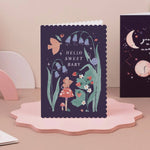 Sister paper co greeting card with floral design and 'Hello Sweet Baby' text on a pink stand.