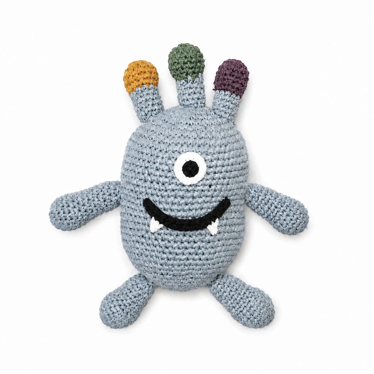 A crocheted monster plush toy in light blue-gray yarn, featuring three colorful antennae in orange, green, and purple, a single large embroidered eye, a black stitched smile, and small white teeth, set against a plain white background.