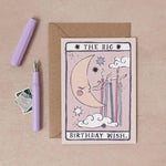 A tarot-style birthday greeting card reading 'THE BIG BIRTHDAY WISH.' is shown on a beige surface with a kraft envelope, a lavender pen, and a small postage stamp by sister paper co.