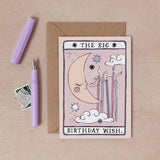 A tarot-style birthday greeting card reading 'THE BIG BIRTHDAY WISH.' is shown on a beige surface with a kraft envelope, a lavender pen, and a small postage stamp by sister paper co.