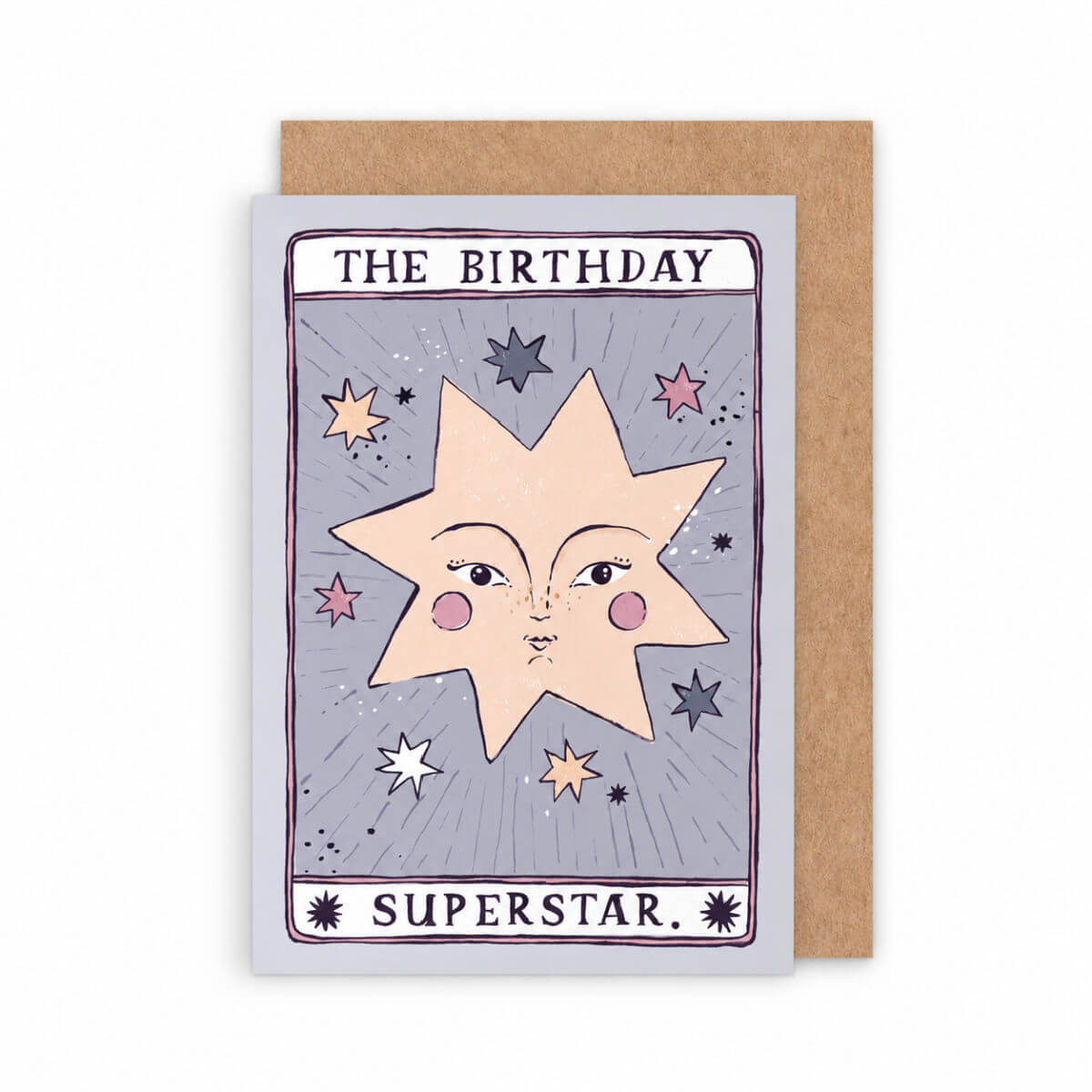 A greeting card with a kraft paper envelope behind it. The card features a tarot-card-style design with the text 'THE BIRTHDAY SUPERSTAR by sister paper co