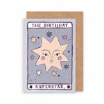 A greeting card with a kraft paper envelope behind it. The card features a tarot-card-style design with the text 'THE BIRTHDAY SUPERSTAR by sister paper co