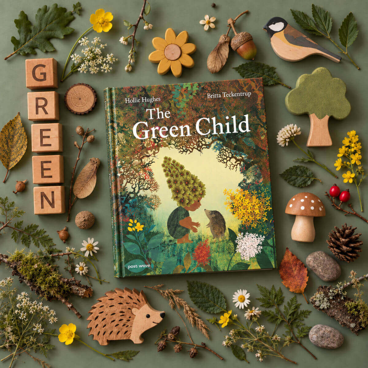 The Green Child children's book by Helle Huighe and Birta Eckenrump is displayed in a styled flat-lay arrangement on a muted green background, surrounded by nature-themed props including wooden letters spelling GREEN, a bird cutout, mushrooms, acorns, pinecones, and small flowers.