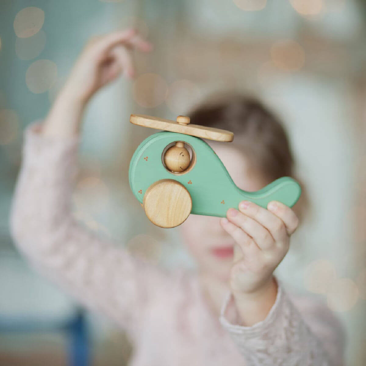Child holding  wooden toy helicopter handmade by friendly toys