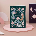 Birthday card with floral design and 'Happy Birthday' text on a pink stand illustrated by sister paper co.