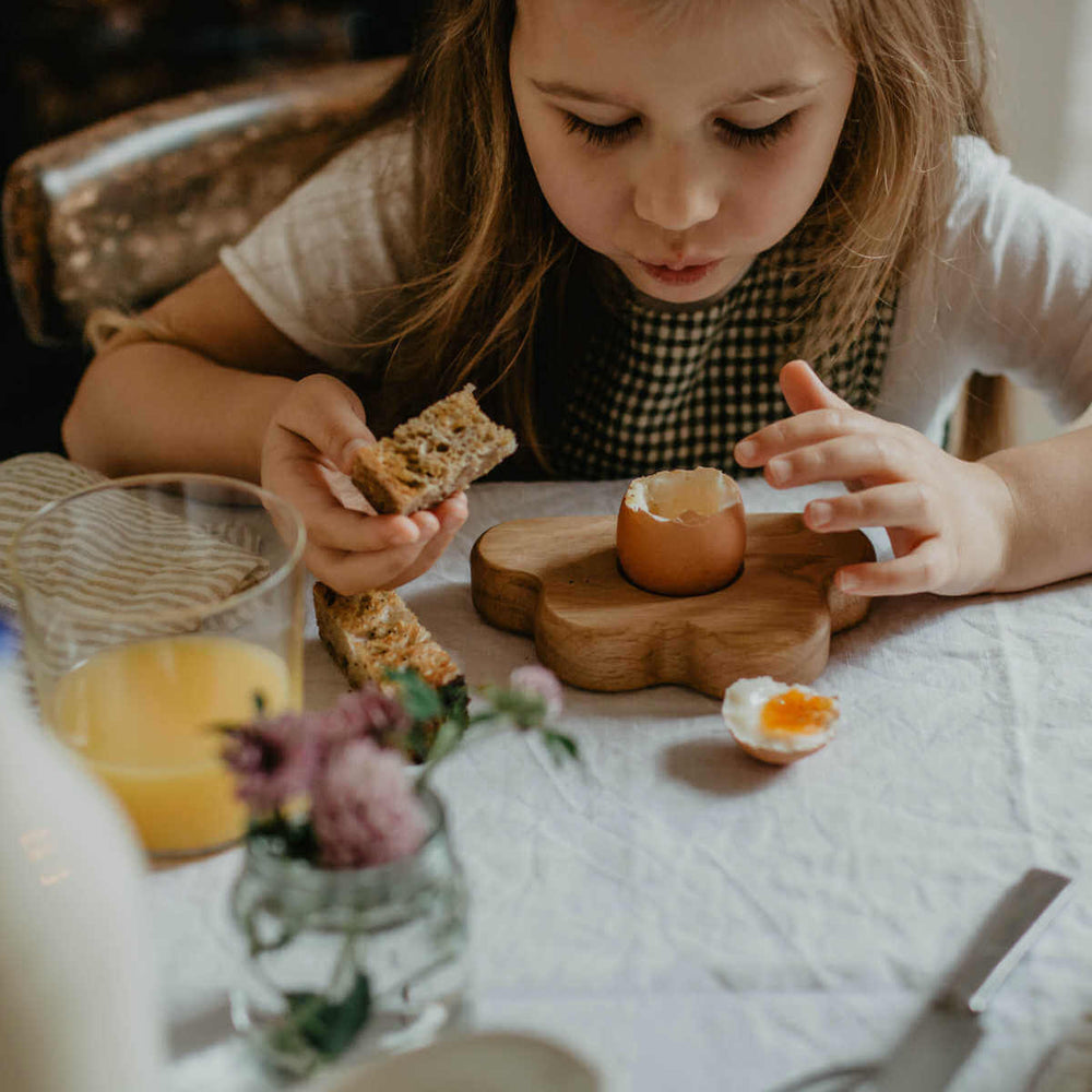 children's handcrafted wooden egg cup in cloud design, dippy egg and soldiers breakfast eaten by child - blue brontide
