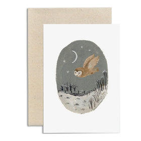 Greeting card featuring an illustration of an owl at twilight flying in front of a moonlit landscape with trees and a night sky background. The card is paired with a beige envelope. By British illustrator Gemma Koomen.